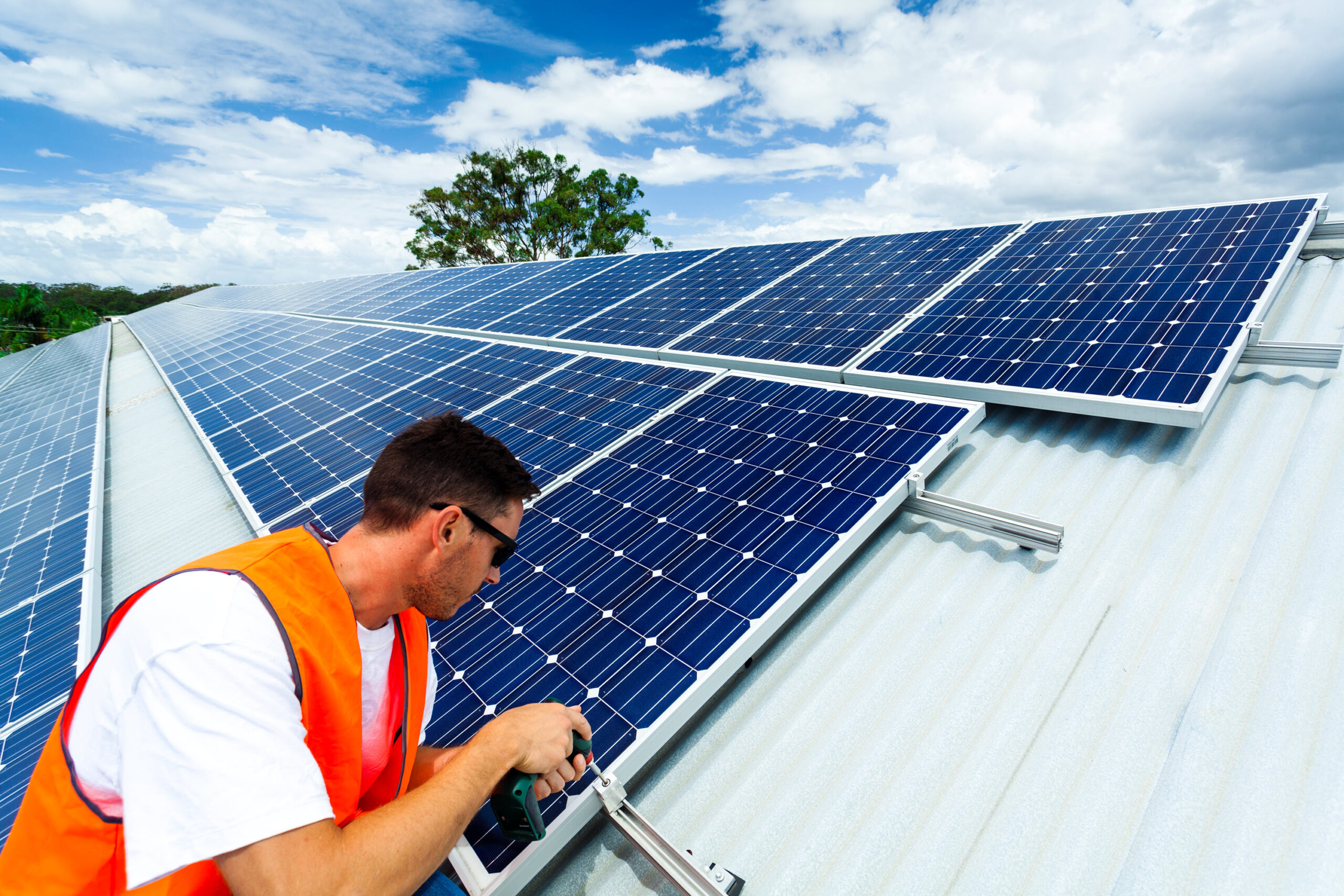 A worker on a roof maintaining a solar panel system