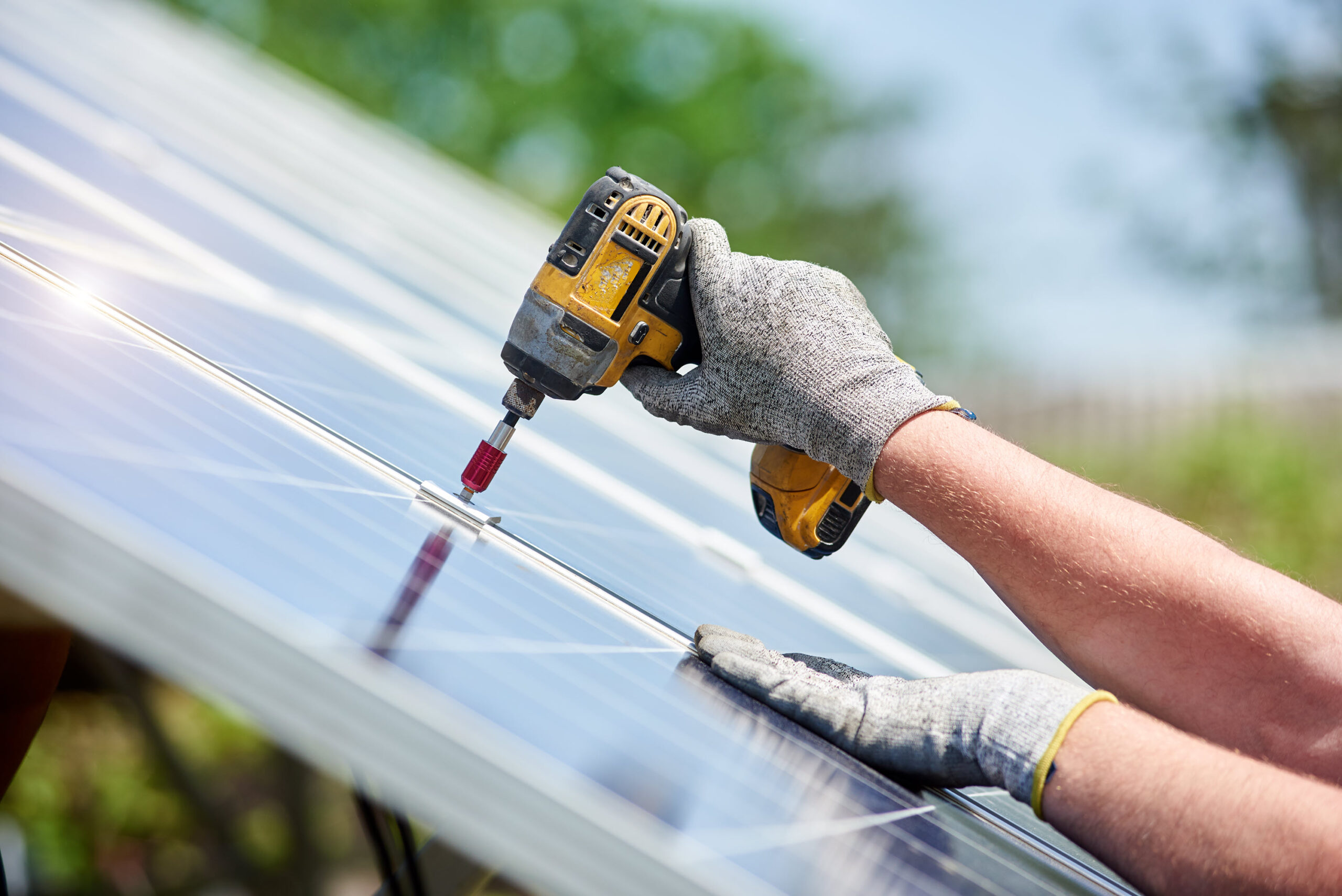 A worker drilling on a solar panel