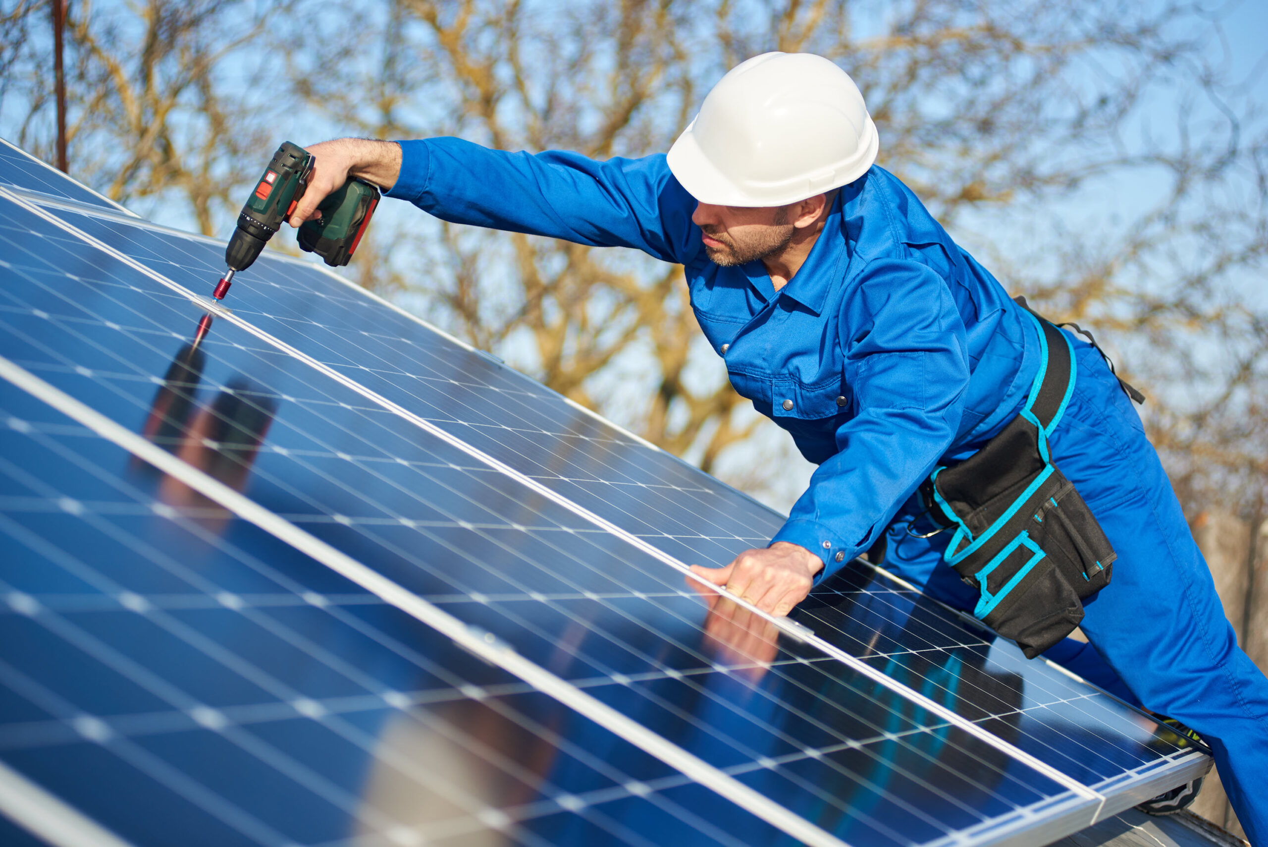 A worker drilling on solar panels